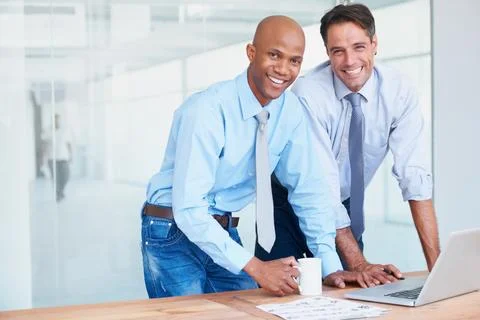 Dynamic duo. Two co-workers smiling while working in the boardroom together. Stock Photos