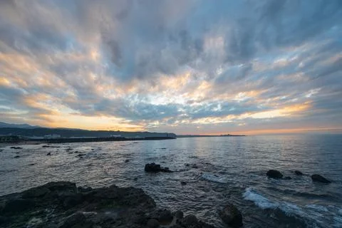 Dynamic fast moving clouds and red sunset. rocky coast. Stock Photos