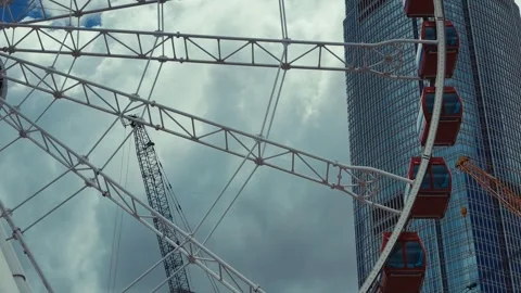 A dynamic Ferris wheel in a bustling Hong Kong cityscape, with red gondolas 库存影片 338311398