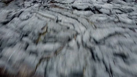 Dynamic flight over a cooling field of black lava revealing a smoking Vidéo 163967597