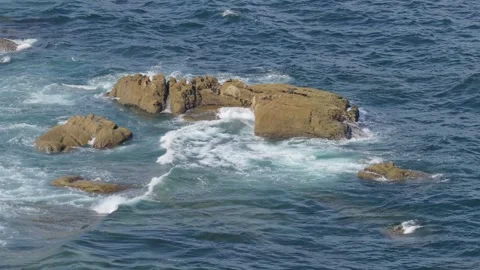 Dynamic footage of ocean waves crashing and swirling around rugged coastal rocks Stock Footage 346711014