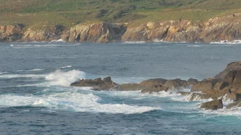 Dynamic footage of ocean waves crashing against rugged rocks along the shoreline Stock Footage 346711140