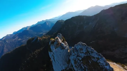 Dynamic FPV dives along striking rock formation in the mountains on sunny day Stock Footage 296582238