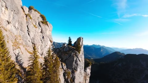 Dynamic FPV dives along striking rock formation in the mountains on sunny day Stock Footage 296582273