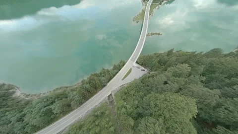 Dynamic FPV drone panorama of forest and lake with mountains and bridge dam 動画素材 135597768