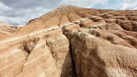 Dynamic FPV drone pullback descending from Aktau Mountains in Altyn Emel. Video stock 334726931