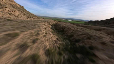 Dynamic Fpv drone shot of desert landscape, surrounded by green fields Stock Footage 236763314