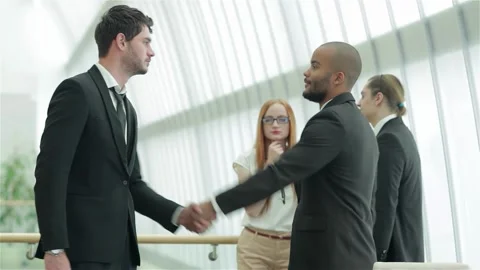 Dynamic handshake between two confident businessmen in a modern office Stock Footage 311806936