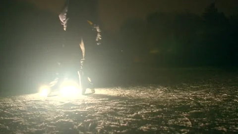 Dynamic ice skater performs bold jumps with bright backlit effects in darkness Видео 347335423