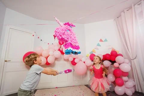 Dynamic image of small boy hitting unicorn pinata at bday party Stock Photos