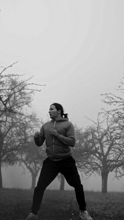 A dynamic individual engaging in athletic movement amidst a foggy and mystical Video stock 309245243
