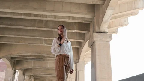 A dynamic low-angle parallax shot of a woman smiling under a bridge in the Stock-Footage 283346356