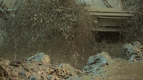 Dynamic low-angle a powerful utility vehicle racing through mud Stock Footage 344877072