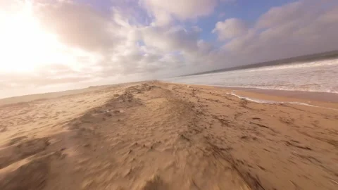 Dynamic low-angle shot moves along wet sand meeting ocean water Stock Footage 345149573