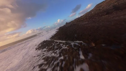 Dynamic low-angle view of ocean waves breaking over dark volcanic rock Stock Footage 344551316