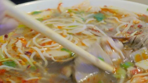 Dynamic macro shot of spicy vietnamese beef noodle soup with chopsticks Video stock 337153258