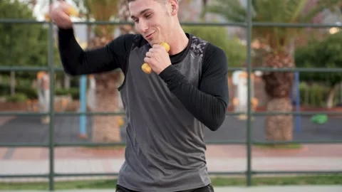Dynamic Morning Routine: Guy's Shadowboxing Session on Palm-Covered Basketball Stock Footage 243169691