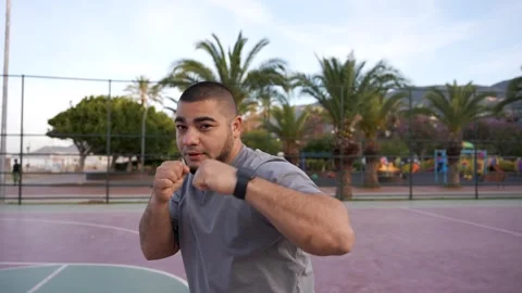 Dynamic Morning Workout: Guy's Shadowboxing Session on Palm-Adorned Basketball Stock Footage 243170147