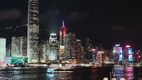 A dynamic night view of Hong Kong's skyline from a moving vessel across Victoria Stock Footage 338280463