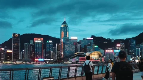 A dynamic nighttime view from a waterfront promenade in Hong Kong, capturing the Stock Footage 338280327