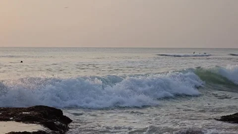 Dynamic Ocean Wave Breaking Near Surfers at Dreamland Beach, Bali at Dusk Stock Footage 340390964