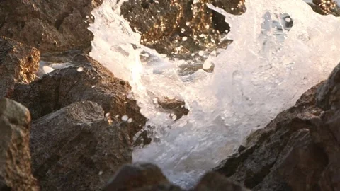 Dynamic ocean wave splashes water violently against dark coastal rocks Stock Footage 337410710
