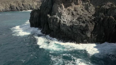 Dynamic Ocean Waves Breaking on Dark Volcanic Cliff Face and Rugged Coastline Stock Footage 320605234