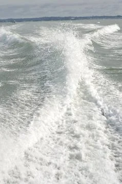 Dynamic ocean waves crash creating white foam trails behind a moving boat o.. 写真素材