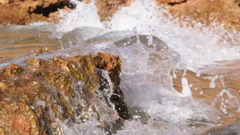 Dynamic ocean waves crashing fiercely against rugged coastal rocks in sunlight Stock Footage 337409629