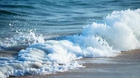 Dynamic ocean waves crashing on sandy coastline creating sea foam and spray.. Stock Footage 321948543