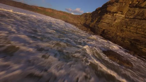 Dynamic ocean waves hit rocks under warm sunset glow Stock Footage 344551052