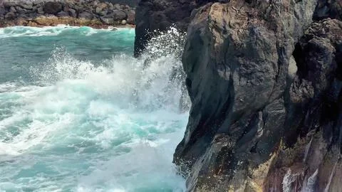 The dynamic ocean waves powerfully and majestically crash against the rugge.. Stock Photos