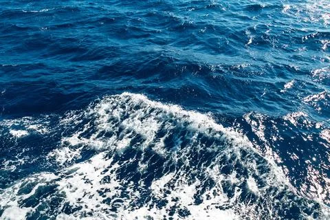 Dynamic ocean waves with sunlit blue waters and white foam patterns Stock Photos