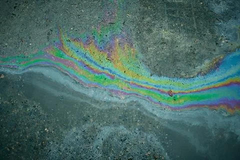 A dynamic puddle of gasoline creates impressive iridescent reflections on dark Stock Photos
