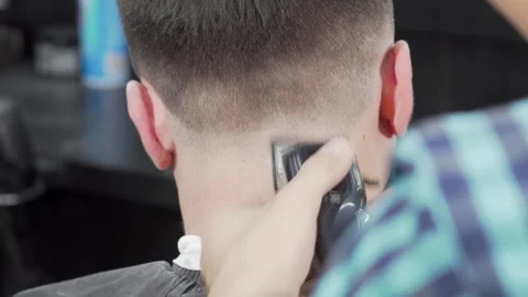 Dynamic rear view of a barber skillfully using a clipper to craft a stylish Video stock 311935694