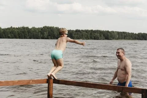 Dynamic, relaxed shot boy jumping into natural lake. child is captured mid .. Stockfoto's