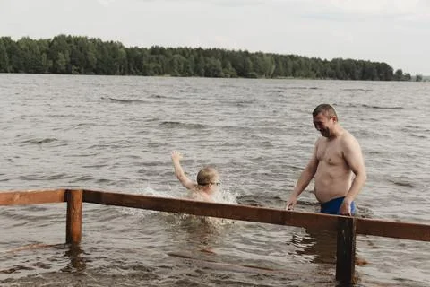 Dynamic, relaxed shot boy jumping into natural lake. child is captured mid .. 库存照片