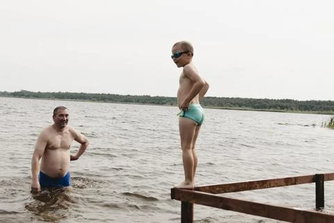 A dynamic, relaxed shot of a boy jumping into a natural lake. The child is ca Photos