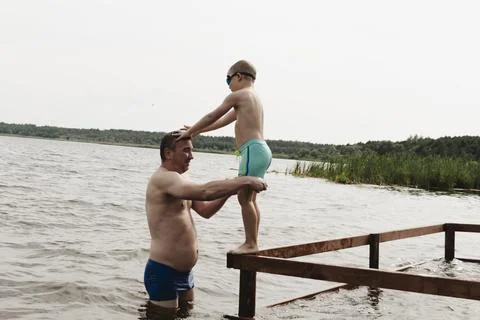 A dynamic, relaxed shot of a boy jumping into a natural lake. The child is ca Fotos Stock