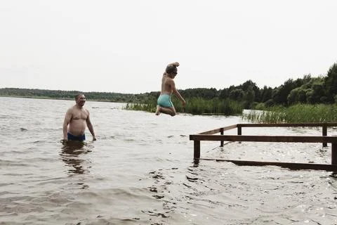A dynamic, relaxed shot of a boy jumping into a natural lake. The child is ca Stockfoto's