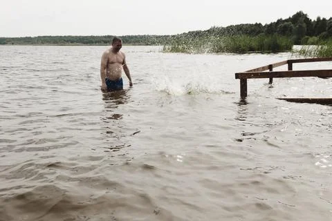 A dynamic, relaxed shot of a boy jumping into a natural lake. The child is ca Photos