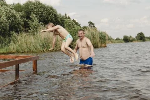 Dynamic, relaxed shot boy jumping into natural lake. child is captured mid .. Stockfoto's