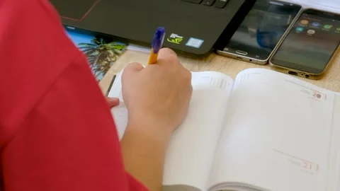 Dynamic Roll Close-Up of Hand Writing in Agenda with Tech Ensemble Stock Footage 254883388