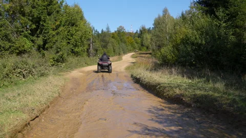 Dynamic shot of an ATV kicking up mud and water on a rustic forest trail Stock Footage 317772035