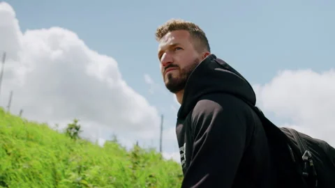 Dynamic shot of young man walking up the hill in nature 4K. Stock Footage 234569170