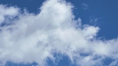 A dynamic sky with fluffy white clouds drifting slowly across a deep, vibrant Stock Footage 338266526