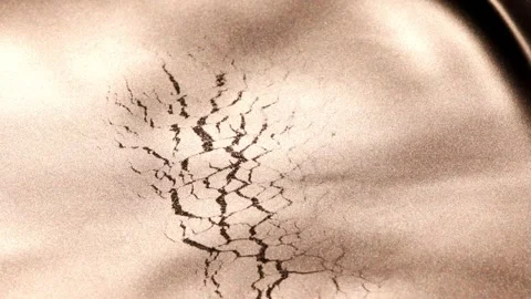 Dynamic slow-motion video of dark golden paint dissolving and merging, revealing Stock Footage 327069542