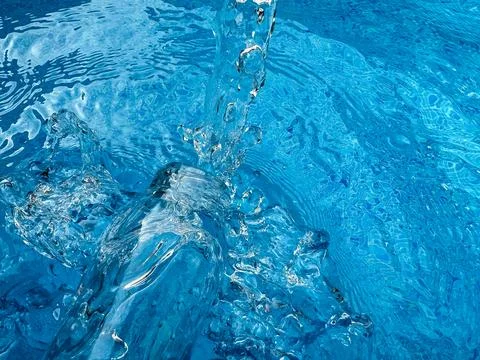 Dynamic splash in crystal clear blue water and glass bottle, creating ripples Stock Photos