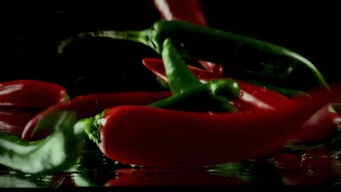 Dynamic splash of fresh red and green chili peppers falling on a wet Video stock 334049600