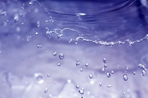 Dynamic splash of water with flying drops, in blue tones 库存照片